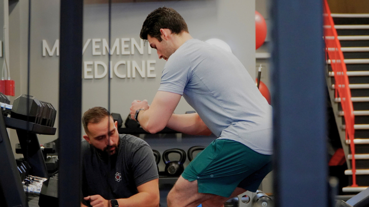 Sami training a man doing side lunges with a elastic band around the knees