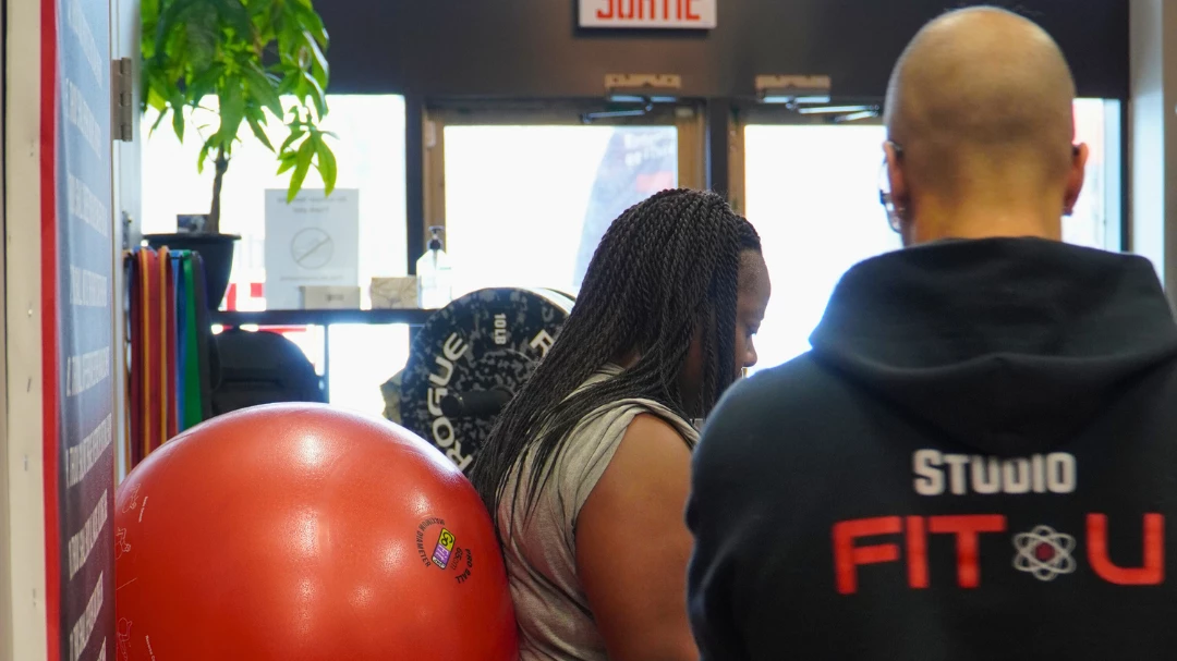 Jimmy avec un client en train de faire des fentes avec un ballon de stabilité.