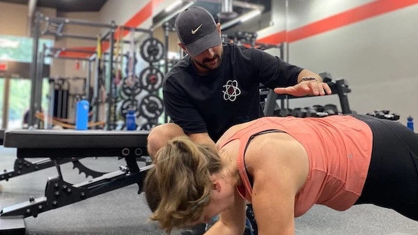 Sami, a trainer at Studio Fit U, assisting a client in perfecting her plank posture, demonstrating the importance of correct technique to optimize performance and prevent injuries.